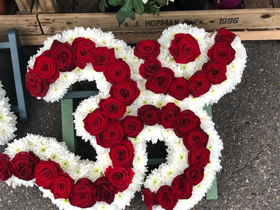 Van Arthur’s red rose Hindu Om Aum floral tribute with a white chrysanthemum border