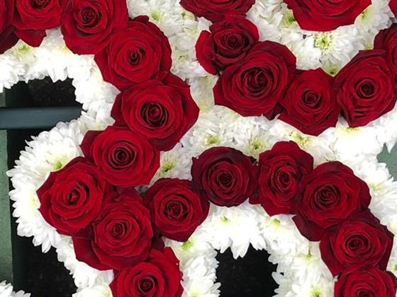 Close-up of Van Arthur’s red rose Aum funeral tribute with white chrysanthemum edging