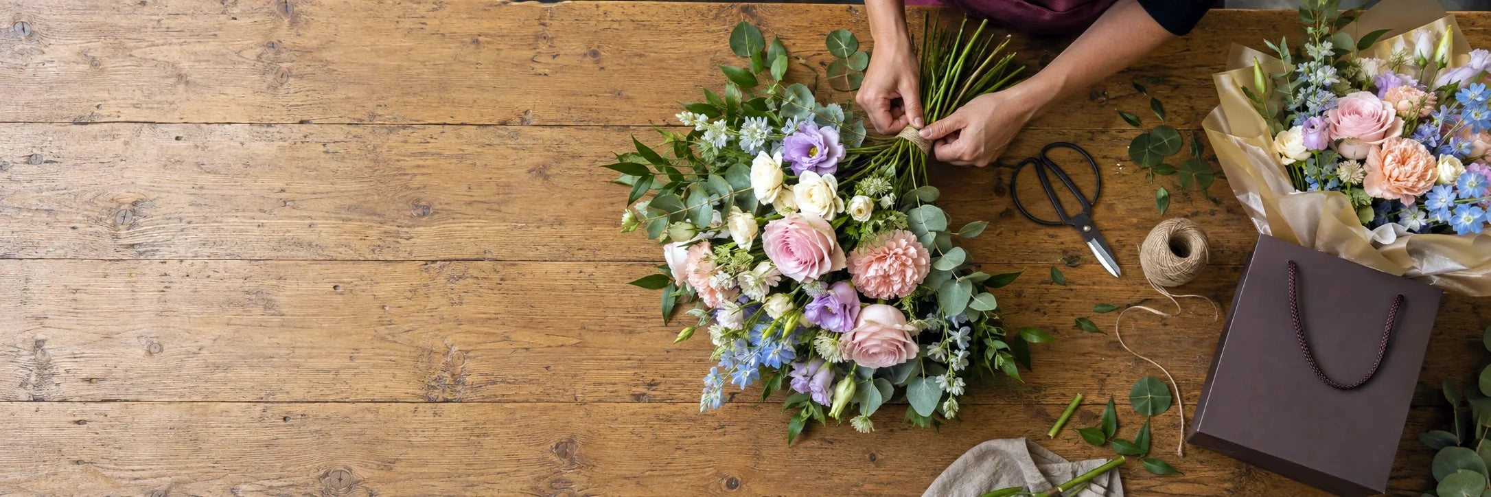Pastel bouquet being arranged at a rustic floristry bench